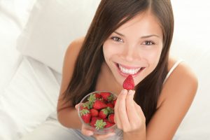 girl with a bright smile eating strawberries
